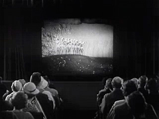 Spectators looking at a cinema screen in a theatre.